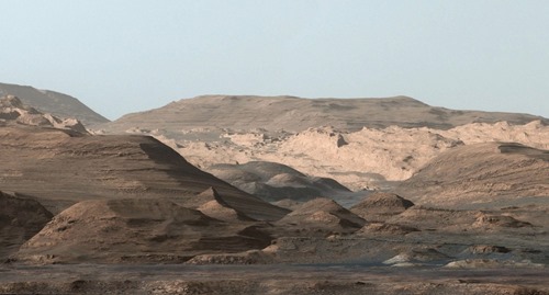 This composite image looking toward the higher regions of Mount Sharp was taken on September 9, 2015, by NASA's Curiosity rover. In the foreground -- about 2 miles (3 kilometers) from the rover -- is a long ridge teeming with hematite, an iron oxide. Just beyond is an undulating plain rich in clay minerals. And just beyond that are a multitude of rounded buttes, all high in sulfate minerals. The changing mineralogy in these layers of Mount Sharp suggests a changing environment in early Mars, though all involve exposure to water billions of years ago. (NASA / JPL-Caltech / MSSS)