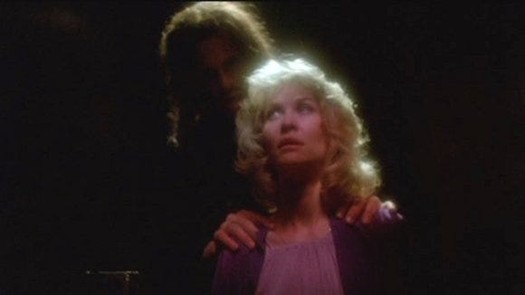 Eddie in the shadows, hands on Karen's shoulders.